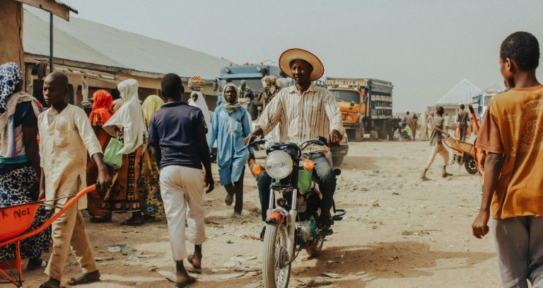 Tourist greeting local African elders in a traditional village with a warm handshake.